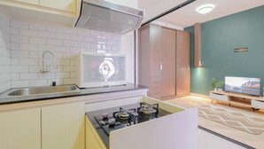 A compact kitchen with a microwave, stove, and sink. - Comfort And Big 1Br At Green Pramuka City Apartment (Jakarta)