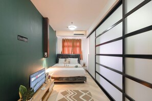 Une chambre à coucher moderne avec un lit, une télévision et une plante.