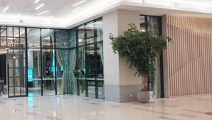 A modern interior with a glass entrance, a potted plant, and a tiled floor. - Minimalist 2Br And Well Design Room At Benson Supermall Mansion Apartment (Surabaya)
