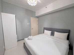 A modern hotel room with a large bed, a wardrobe, and a door. - Minimalist 2Br And Well Design Room At Benson Supermall Mansion Apartment (Surabaya)