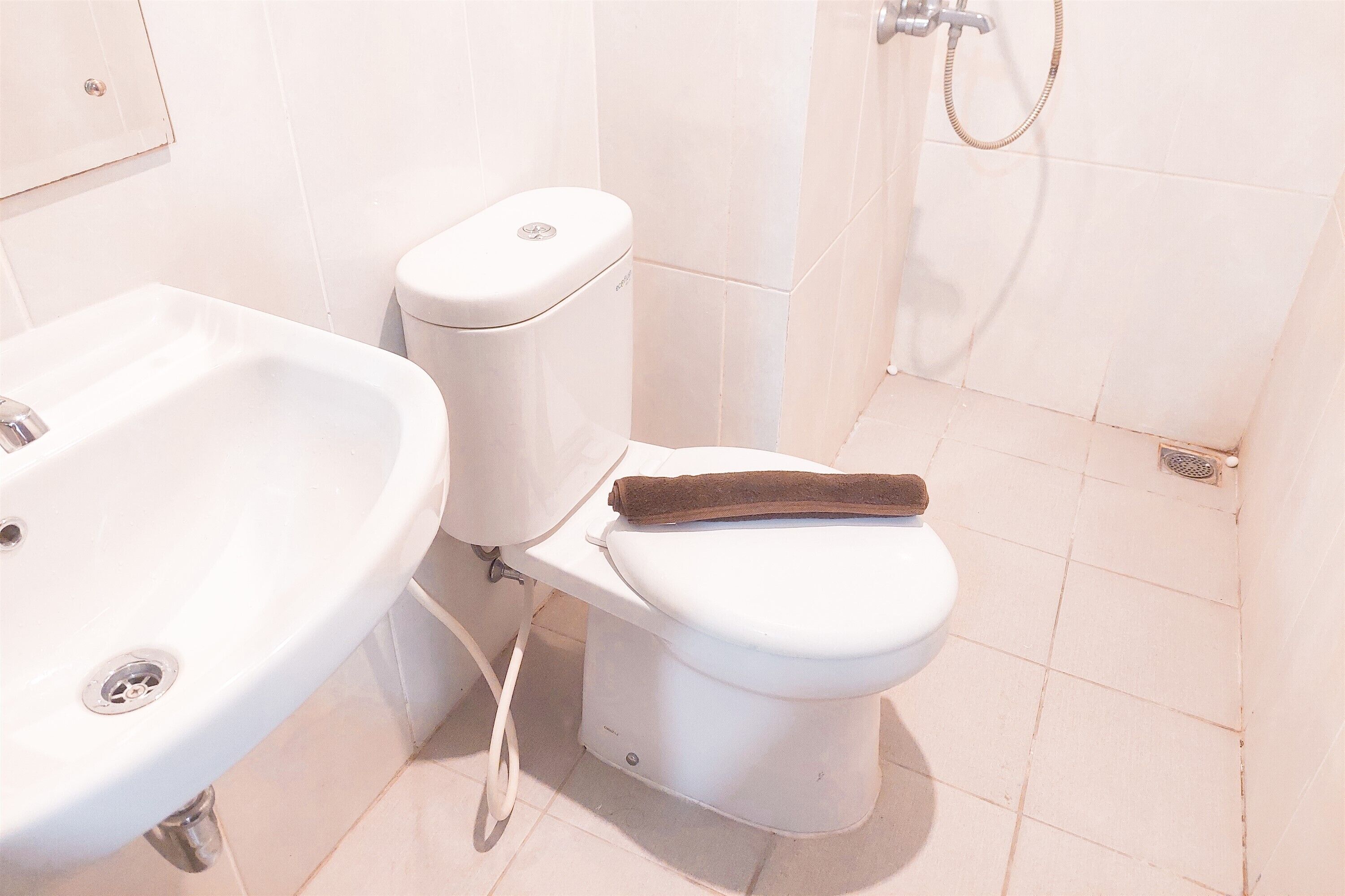 Een badkamer met een wit wastafelmeubel, toilet en douche.