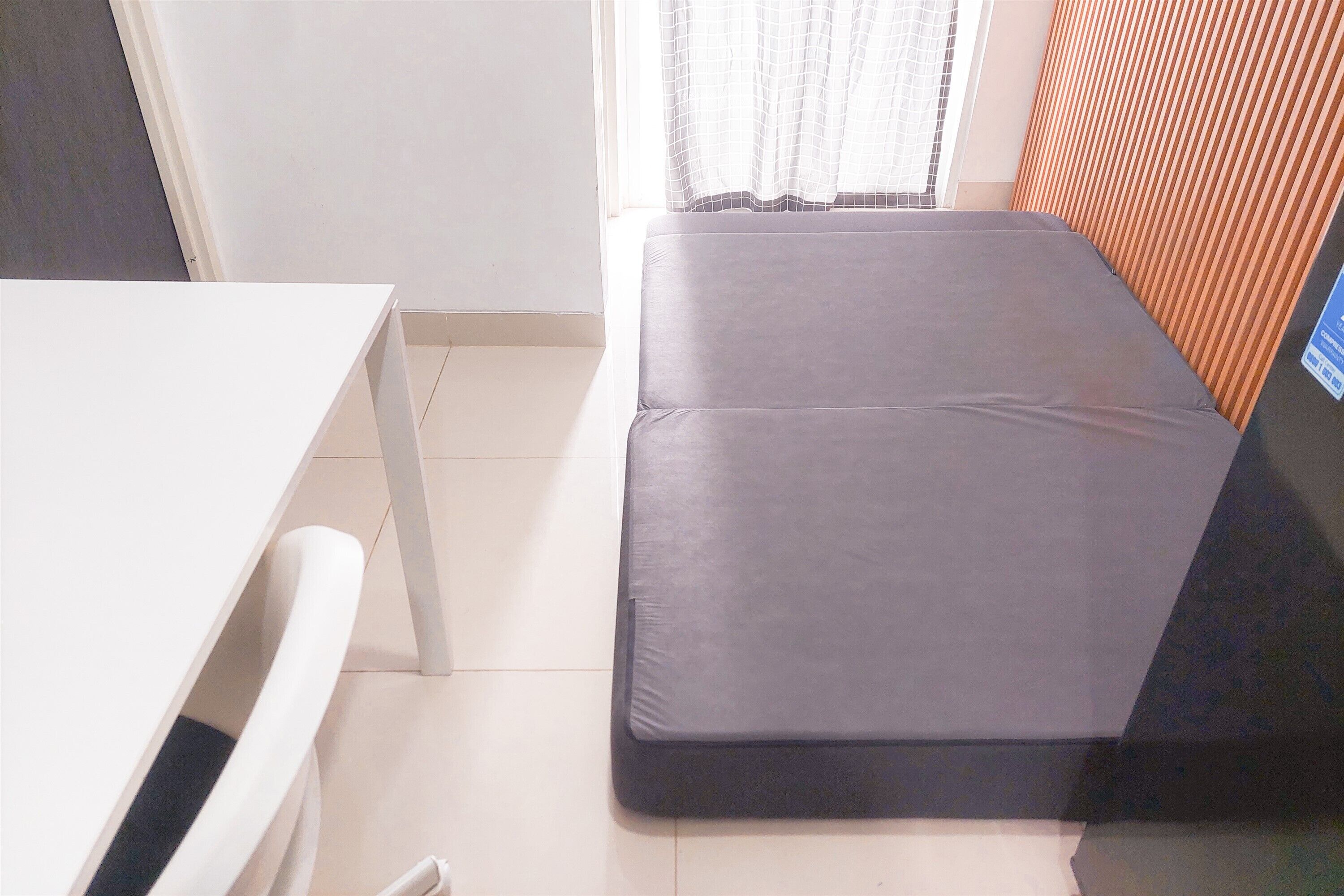 Una habitación con una cama, una mesa blanca y un ventanal con cortinas.