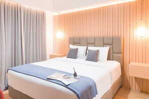 Enjoy a restful stay in this inviting room with a comfortable bed, bedside table, and ample natural light.