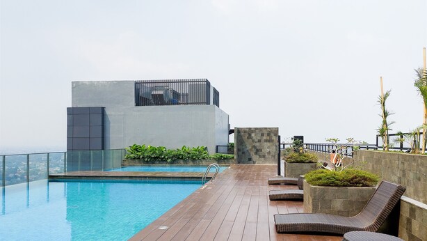 A rooftop pool area with a modern building, lounge chairs, and a view of the city. - Elegant 1Br Without Living Room Apartment Bintaro Embarcadero (South Tangerang)