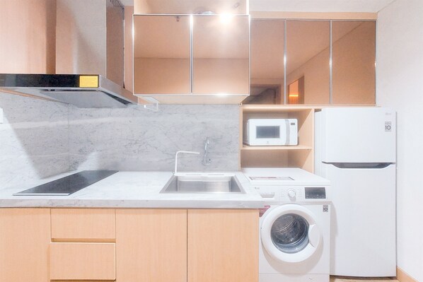 A compact kitchen with a sink, microwave, and washing machine.