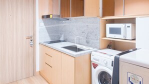 A compact kitchen with a sink, microwave, and washing machine. - Elegant 1Br Without Living Room Apartment Bintaro Embarcadero (South Tangerang)