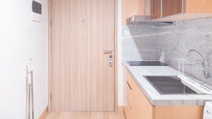 A modern kitchen with a wooden door, a marble countertop, and a stainless steel sink. - Elegant 1Br Without Living Room Apartment Bintaro Embarcadero (South Tangerang)
