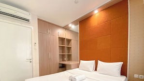 A hotel room with a bed, a wardrobe, and a built-in shelf unit. - Tranquil Abode 1Br Apartment At Parahyangan Residence (Bandung)