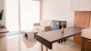 A modern kitchen with a dining table, a sofa, and a refrigerator. - Good Choice And Comfy 1Br Apartment Paramount Skyline (Gading Serpong)