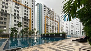 A swimming pool with tiled deck, surrounded by tall residential buildings. - Good Choice And Comfy 1Br Apartment Paramount Skyline (Gading Serpong)
