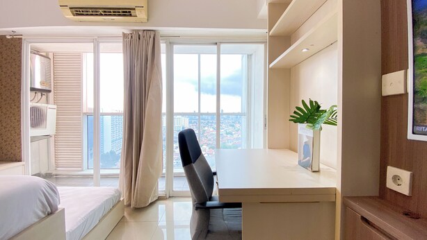 Une chambre d’hôtel moderne, équipée d’un lit, d’un bureau et d’une grande fenêtre avec des rideaux.