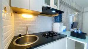 A modern kitchen with a stainless steel sink, black countertop, white cabinets, a gas stove, and a water dispenser.