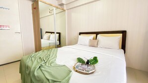 A hotel room with a bed, a green blanket, and a newspaper on the bed.