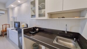 A modern kitchen with white cabinetry, a black countertop, and a stainless steel sink. - Comfortable Studio At Altuz Seturan Yogyakarta Apartment (Depok)