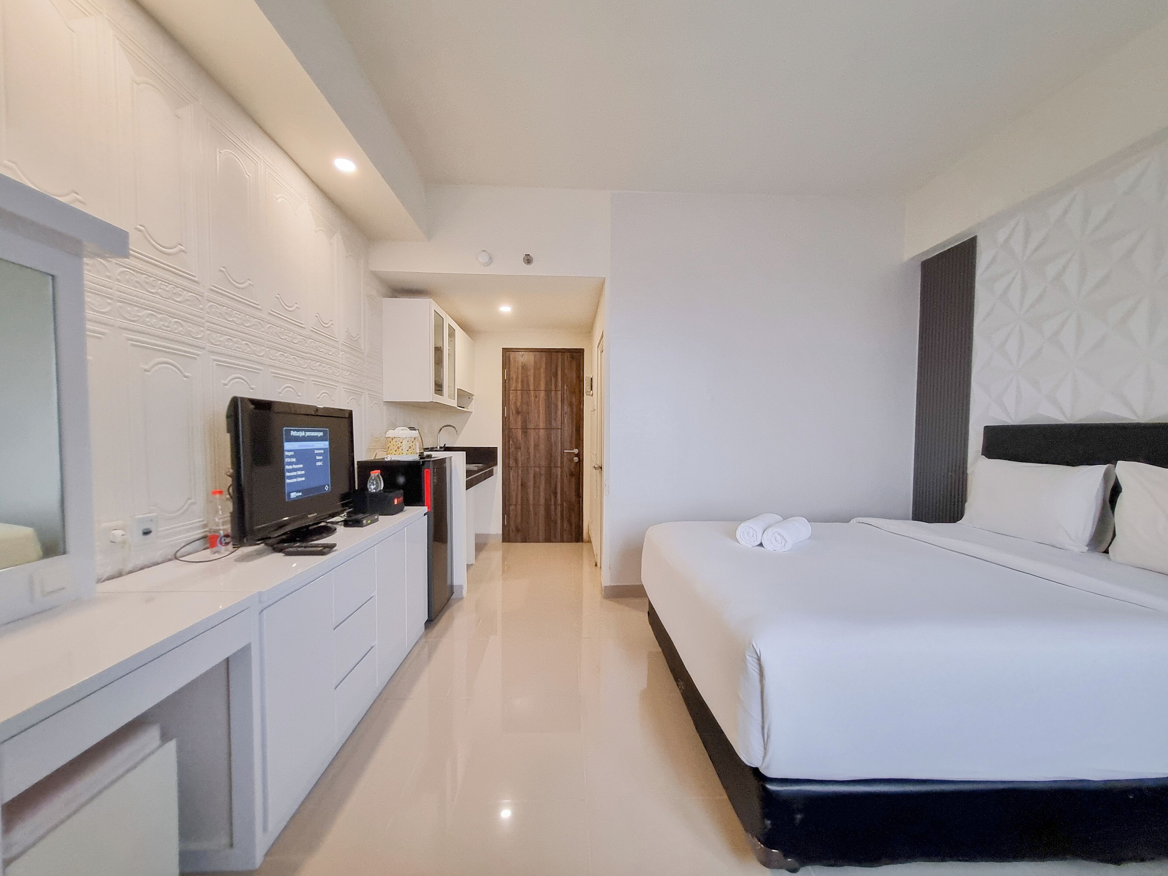 A hotel room with a bed, a desk with a computer, a television, and a bathroom.