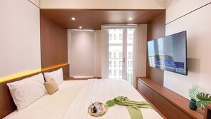 Relax in comfort with a large bed, flat-screen TV, and a potted plant.