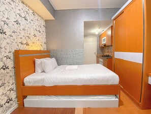 Cozy bedroom with a single bed, kitchenette, and drawer, perfect for a compact retreat.