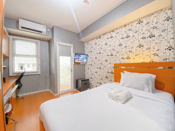 Relax in a cozy space with a comfortable bed, TV, and air conditioning for a restful stay.