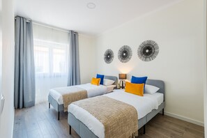 Habitación doble con dos camas, una ventana con cortinas y decoración en la pared.