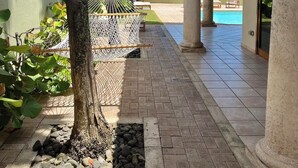 A resort pathway with palm trees, a hammock, and a view of the ocean.