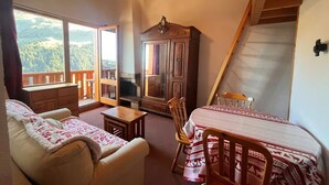 A cozy room with a sofa, a small table, a wooden cabinet, and a bed with a patterned bedspread. - Apartment Chalet Méribel Mottaret ! Ski 3 minutes' walk (Les Allues)