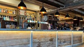 A bar area with wooden paneling, a counter, and hanging pendant lights. - Superior Stays at Sunset Lodge (Ilfracombe)