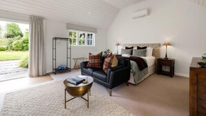 Ett modernt sovrum med en svart lädersoffa, ett sängbord med en lampa och ett stort fönster med utsikt över omgivningen.