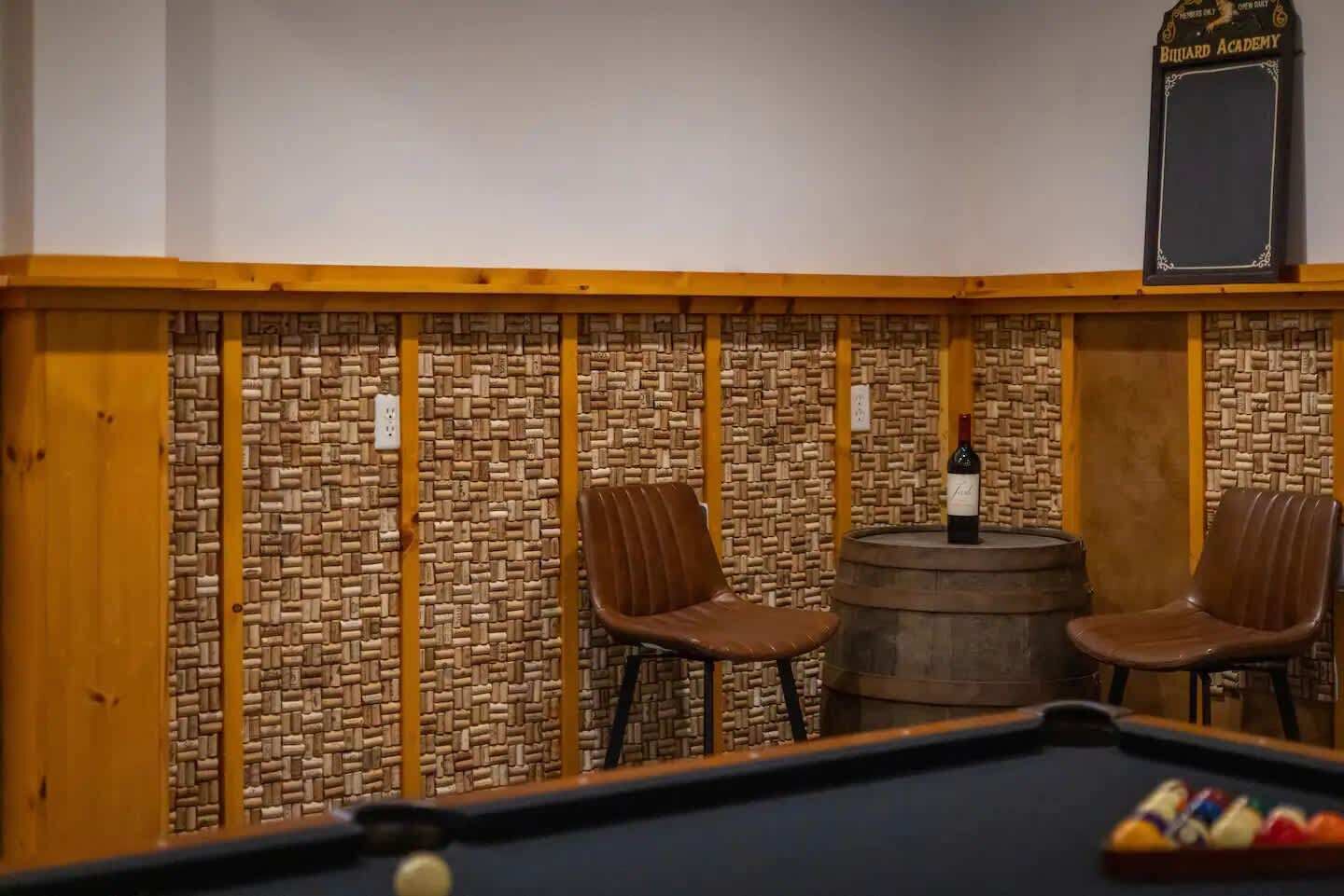 Una sala de billar con dos sillas, una mesa de billar y un barril.