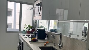 A modern kitchen with white cabinets, a sink, and a window providing natural light. - Amazonas/IBC/PCD/Congonhas Airport/Interlagos Racetrack/Expo Transamerica. (Campo Grande)