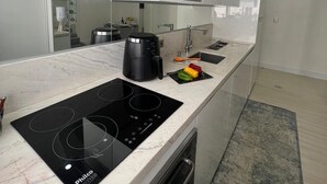 A modern kitchen with a black induction cooktop, a coffee maker, and a microwave above the counter. - Amazonas/IBC/PCD/Congonhas Airport/Interlagos Racetrack/Expo Transamerica. (Campo Grande)