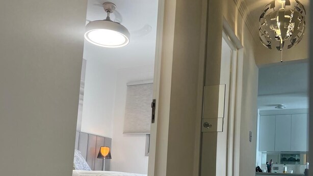 A modern interior with a glass partition, a bed with white bedding, a ceiling fan, and a kitchen area visible through the partition. - Amazonas/IBC/PCD/Congonhas Airport/Interlagos Racetrack/Expo Transamerica. (Campo Grande)
