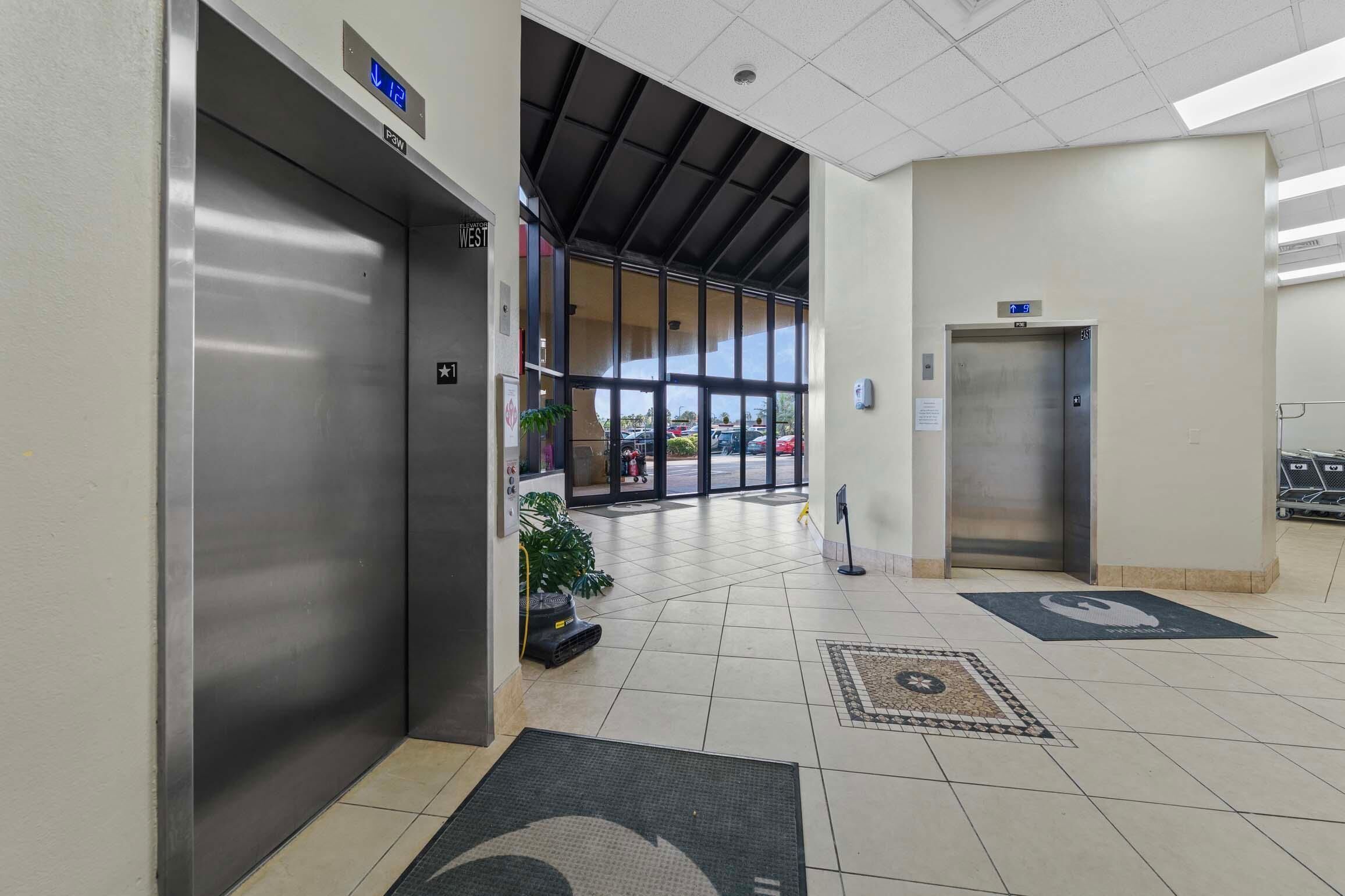 Eine saubere, moderne Lobby mit zwei Aufzügen, einer beschriftet mit 'P3W' und der andere mit einem Schild, das nach Westen weist.