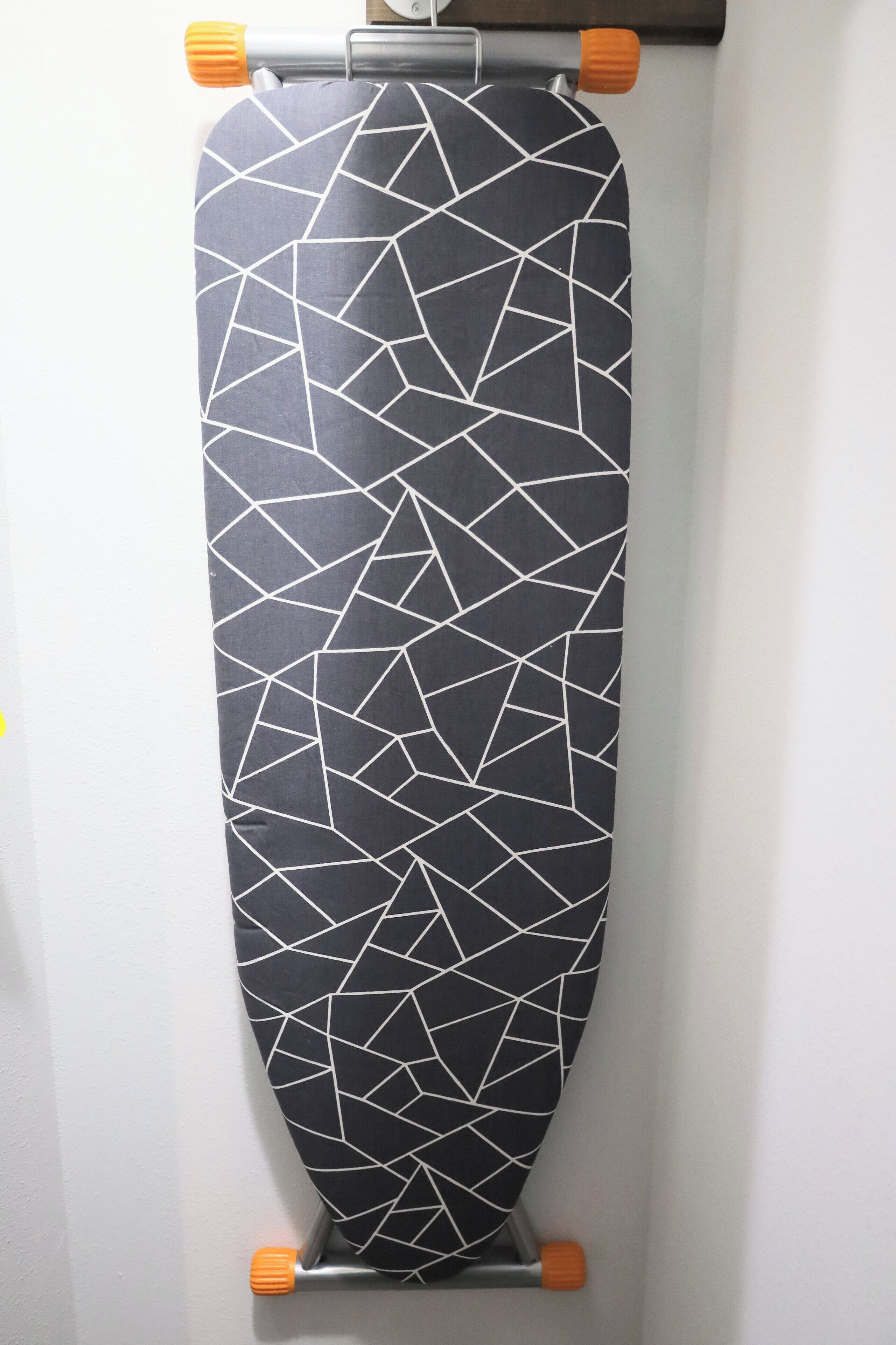 Une planche de surf aux motifs noir et blanc, appuyée contre un mur.