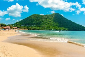 A beach with clear turquoise waters, a sandy shore, and a lush green hill in the background. - Paradise Haven - Saint Lucia "Your Perfect getaway awaits" (Gros Islet)