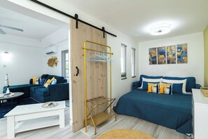 Un dormitorio moderno con cama, sofá, mesa de centro y un tendedero en la pared.