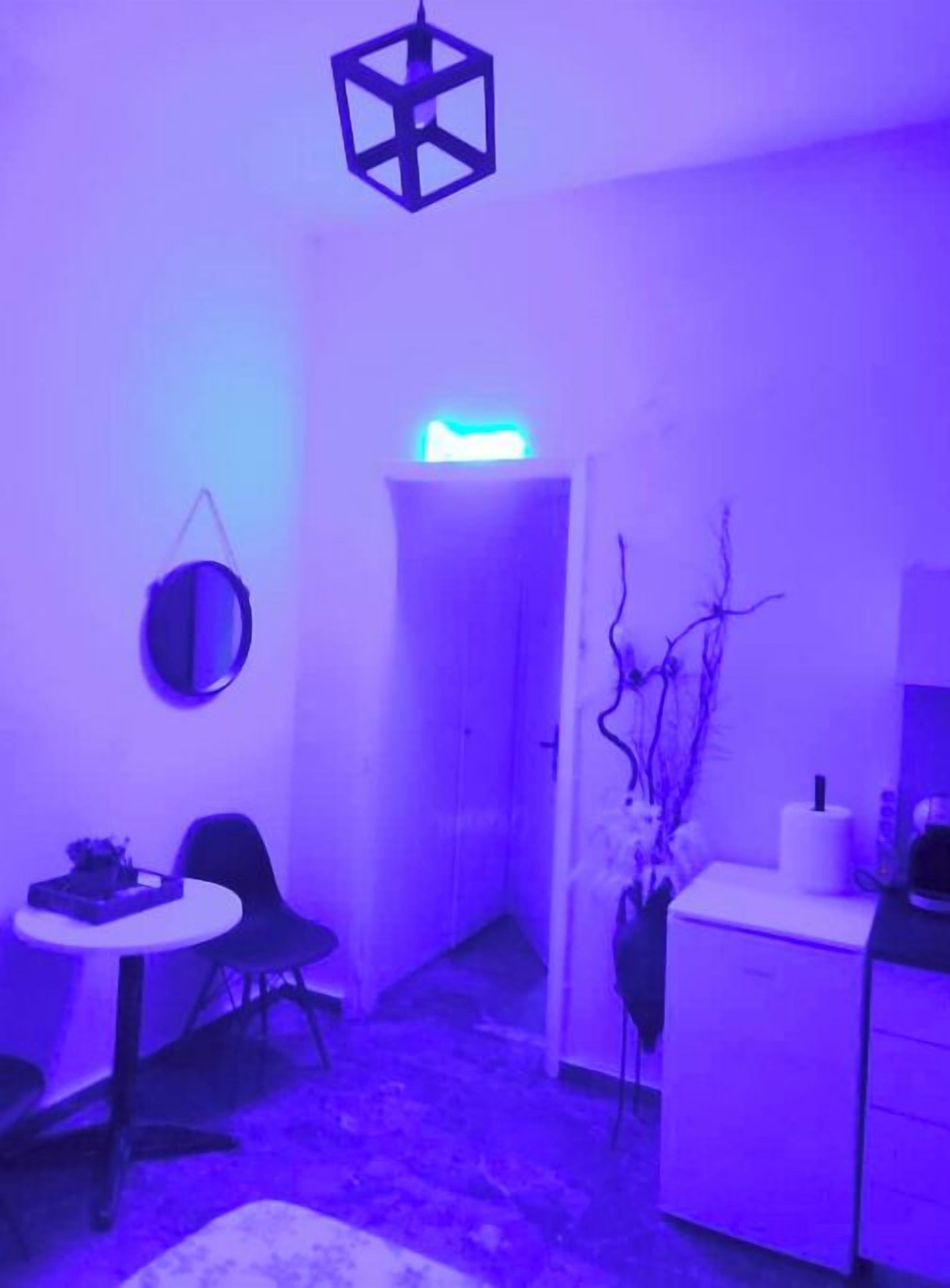 A room with a desk, chairs, a small table, a cabinet, and a hanging light fixture.