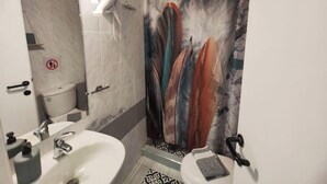A bathroom with a shower curtain featuring feather designs, a sink, and a toilet.