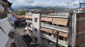 A narrow street with buildings on both sides, featuring balconies and a car parked on the street.