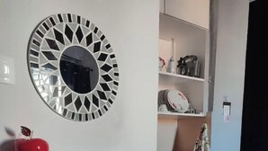 A compact kitchen with a red refrigerator, a decorative wall mirror, and a shelf with kitchen items. - Dream Catcher (Veria)