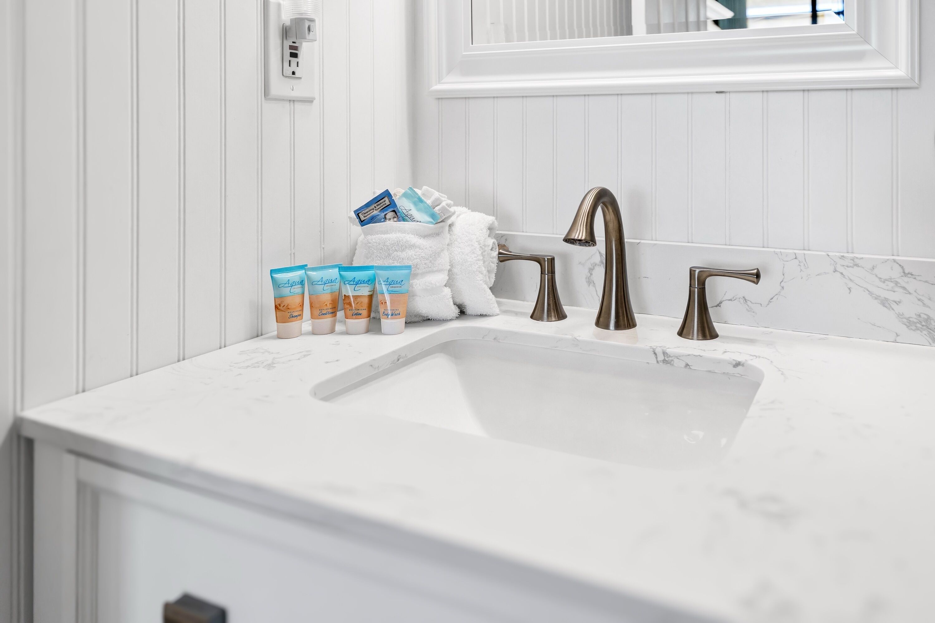 A bathroom with a white sink, two faucets, and a towel rack with toiletries.