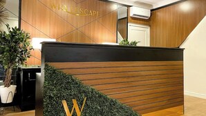 A reception desk with a wooden finish and a large 'W' logo. - WHTYESCAPE SERVICED APARTMENTS (Abuja)