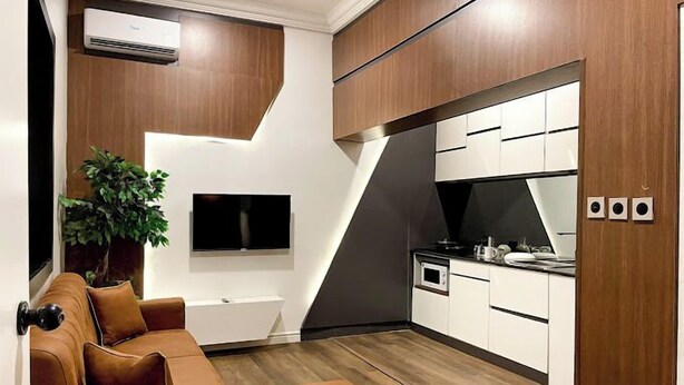 A modern kitchen with white cabinets, a built-in oven, and a black countertop. - WHTYESCAPE SERVICED APARTMENTS (Abuja)