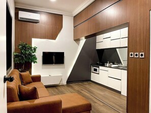Apartamento família, sacada, vista para a cidade | Área de estar | TV de tela plana