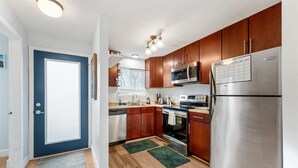 A modern kitchen with wooden cabinets, stainless steel appliances, and a blue door. - Escape to the scenic heights of Hood River (Hood River)
