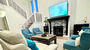 Una sala de estar moderna con chimenea, televisor y una escalera.