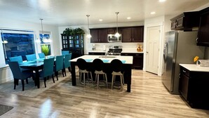 Una cocina moderna con armarios oscuros, electrodomésticos de acero inoxidable y una isla central con taburetes de bar.