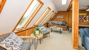 Un acogedor espacio tipo loft con vigas de madera, un sofá, una mesa de centro y una mesa de comedor.