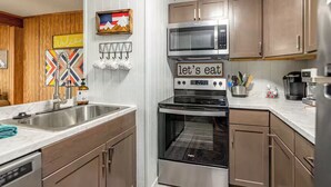 Una cocina moderna con electrodomésticos de acero inoxidable, armarios de madera y un cartel que dice 'Welcome'.