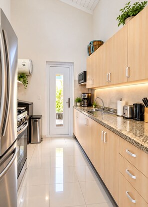 A modern kitchen with stainless steel appliances, wooden cabinets, and a granite countertop. - Beija Flor Entire home in Oranjestad, Aruba (Opal)