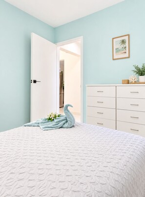 A bedroom with a bed, a dresser, a door leading to another room, and a framed picture on the wall. - Beija Flor Entire home in Oranjestad, Aruba (Opal)